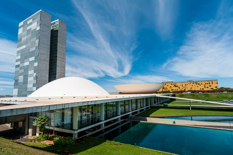 Prédio do Congresso num dia ensolarado. À frente há um espelho d