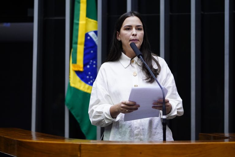 Deputada Maria Arraes sorri olhando para a câmera. Ela é uma mulher jovem, branca de cabelos longos e escuros