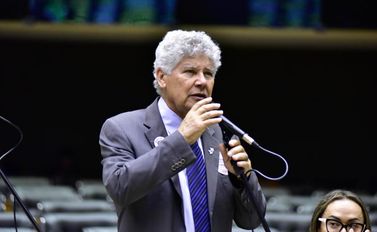 Deputado Chico Alencar fala ao microfone. Ele é claro, tem o cabelo cacheado e grisalho, e usa um terno cinza